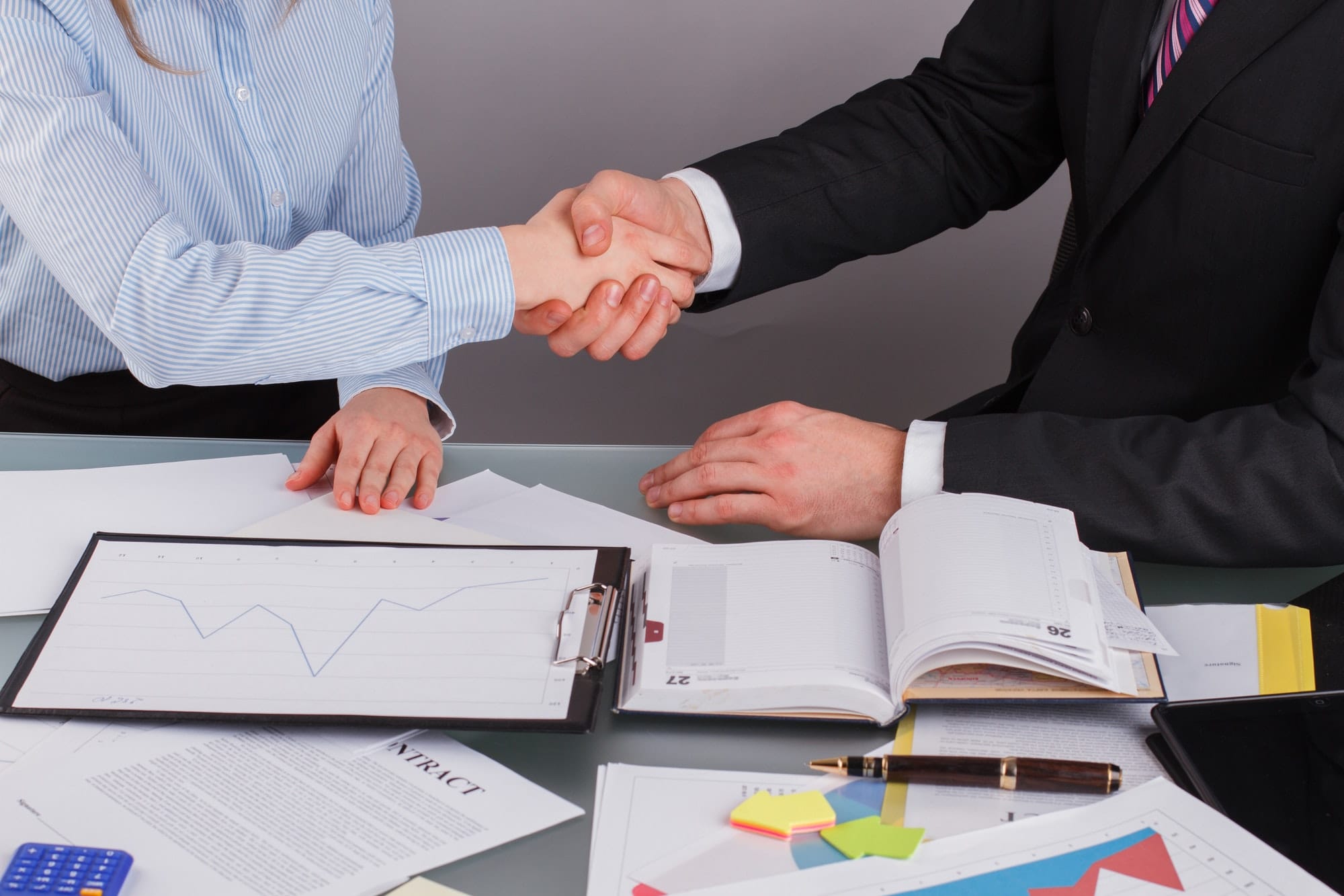 Close up of business handshake at meeting or negotiation above the desk in office.